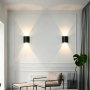To LEDlife 2W CURVE sorte op/ned-væglamper lyser på væggen i en lys stue.