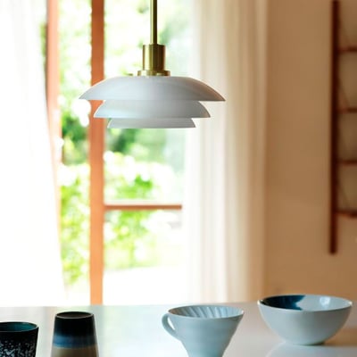 Dyberg Larsen DL20 pendel i opalglas og messing med en diameter på 200 mm, ophængt i et rum med dagslys.