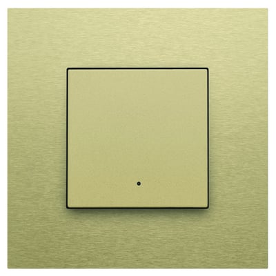 Niko 1-tryk med LED i guld med en sort ramme, viser en central trykflade med en lille prik i midten.