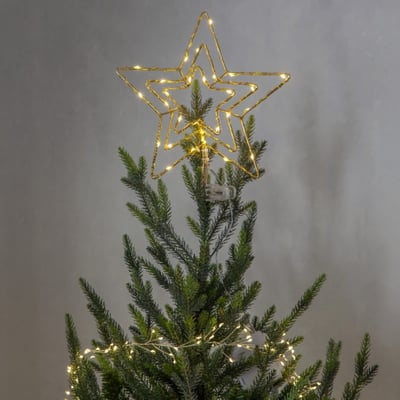 Star Trading Topsy messing topstjerne med 30 varme hvide LED lys på et juletræ med grå baggrund.