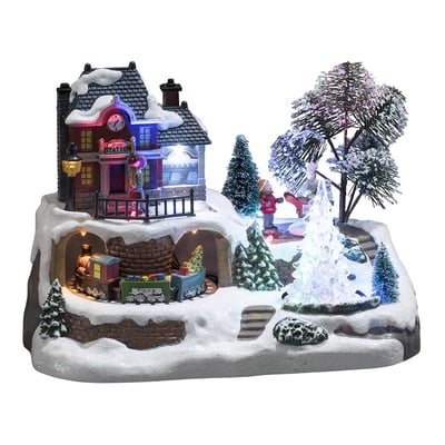 Konstsmide juleby set fra siden, der viser det mekaniske tog, huset, juletræer og snedækket landskab med LED lys.