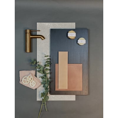 Moodboard med Dansani Mido+ vaskeskabsmaterialer og tilbehør, inklusiv messingvandhane, fliser og dekorationsgrene.