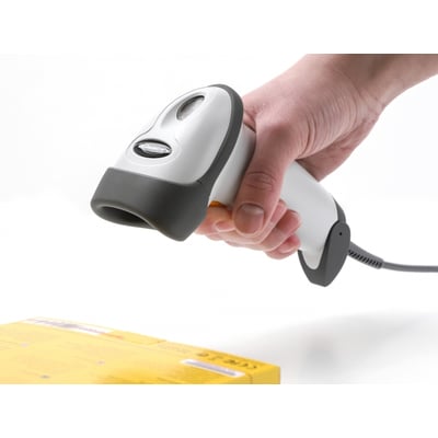 DeLock USB 1D barcodescanner i hvid og grå holdes over en gul æske med stregkode.