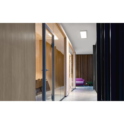 SG Armaturen Sense Surface LED-armatur monteret i et moderne kontormiljø med glasvægge og træpaneler.
