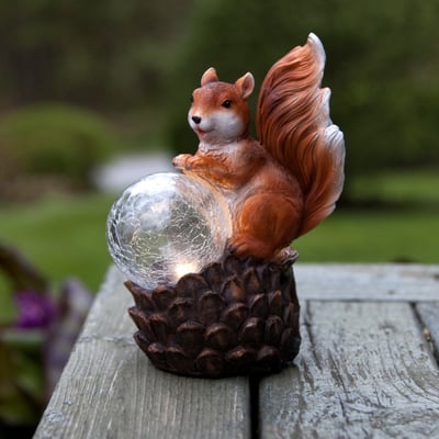 Dekorativ Star Trading egern solcellelampe, fremstillet af porcelæn, med lysende kugle placeret på træbord.