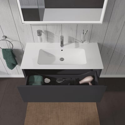 Duravit L-Cube vaskeskab i grafit mat, med skuffen åben og vist fyldt med badeværelsestilbehør som hårtørrer og børster.