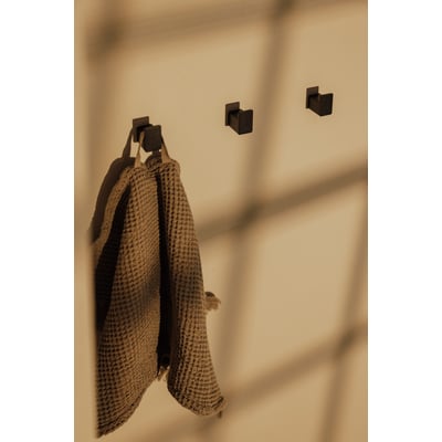Metallbude Palo vægknage i sort, vist med en brun vaffelvævet håndklæde hængende på den.