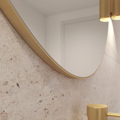 Nærbillede af kanten på Loevschall Refine spejlet med børstet messingramme og en tekstureret væg.