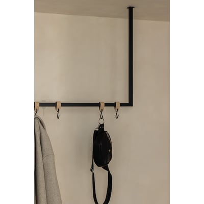 Metallbude Rubi tøjstativ i sort metal, lofthængt med 100 cm bredde og 60 cm højde, vist med en jakke og en taske.