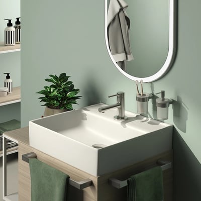 HeFe PIREN tandglas i børstet stål monteret på en væg ved siden af en vask med tandbørster.