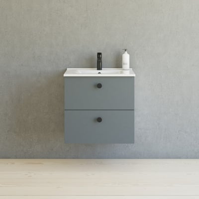 Dansani Button greb i grå med to skuffer, monteret med sorte runde greb, foran betonvæg.