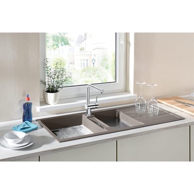Blanco Linus-S-F køkkenarmatur i krom med udtrækstud monteret på et brunt dobbeltsidet vaskebord ved et vindue.