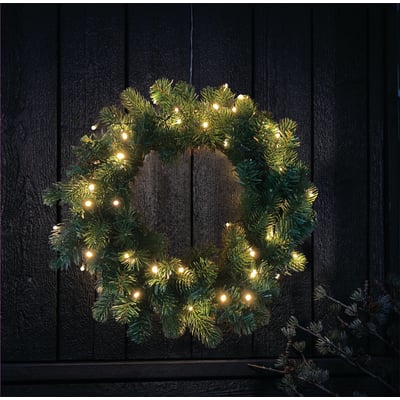 Veli Line grankrans Ø40 cm med 40 varm hvide LED-lys hænger på en mørk trædør, perfekt til juleudsmykning udendørs.