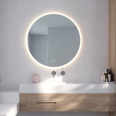 Loevschall Johannesburg rundt spejl, Ø80 cm, monteret på en moderne badeværelsesvæg med lys tændt og reflekterende vask og vandhane.