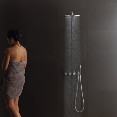 Vola indbygningstermostat med omskifter T2 og ¾'' tilslutning i et moderne badeværelse med en kvinde svøbt i et håndklæde.