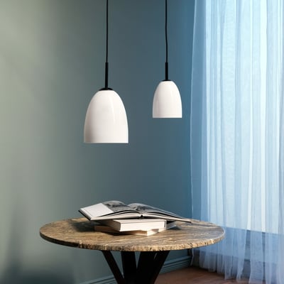 To Dyberg Larsen Jazz pendler D12, hvid opalglas med sort top, over et rundt bord med bog.