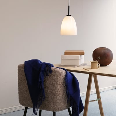 Dyberg Larsen Jazz pendel D18 i opalglas og sort metal, monteret over et arbejdsbord med en stol og dekorative genstande.