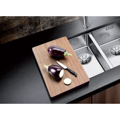 Blanco skærebræt af trækomposit med aubergine og kniv, måler 24x42 cm og ligger ved siden af en køkkenvask.