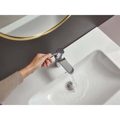 Hansgrohe Waterforms L håndvaskarmatur i krom, vist med en kvindes hånd der betjener et-grebet, mens vand løber i vasken.