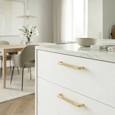 Beslagsboden bøjlegreb i børstet messing, 96 mm, monteret på hvide skuffefronter i et lyst køkken.