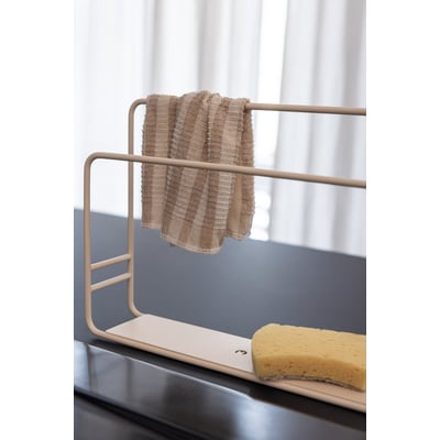 Metallbude Nia karkludholder i creamfarvet metal med et stribet karklud hængende på den øverste stang og en gul svamp på bundpladen.