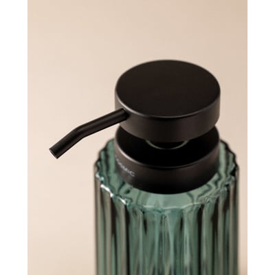 Nærbillede af Cosmic fritstående sæbedispenser i grøn glas med riflet overflade og sort pumpe.