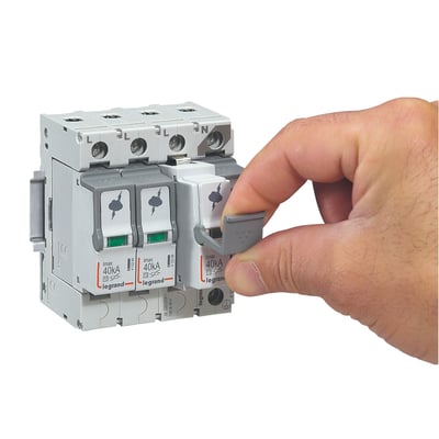 Legrand transientbeskyttelse type 2, 3P+N, med 40kA Imax og plug-in moduler, vist med en hånd der betjener en grå kontakt.