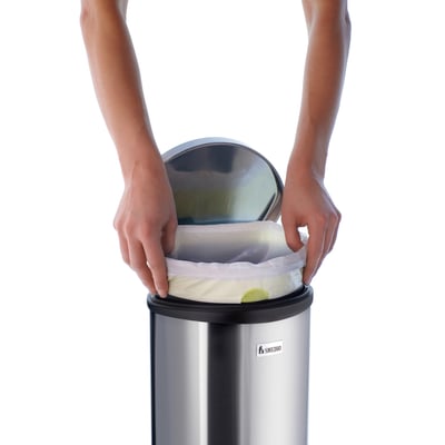 Smedbo outline lite pedalspand i sort belagt rustfrit stål, 6 liters kapacitet, hvor en hånd trækker en plastpose ud.