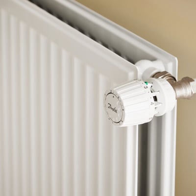 Nærbillede af Stelrad Hygiene radiator med hvid termostatknop og synlige paneler i en let gylden baggrund.