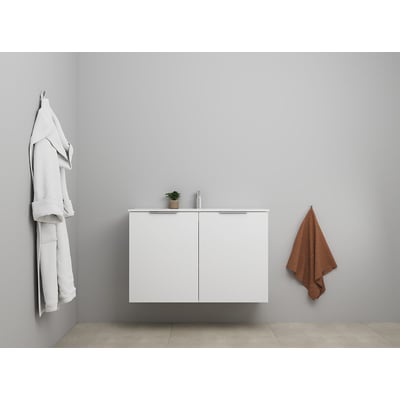 Sanibell Online møbelsæt i mathvid med to låger, monteret på en grå væg, komplet med vask og krom armatur. Et hvidt badekåbe hænger til venstre og et orange håndklæde til højre.