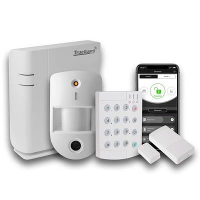 TrueGuard SmartBox startpakke samlet: alarmpanel, bevægelsessensor med kamera, udendørs tastatur, mikro dørkontakt og smartphone med TrueConnect app.