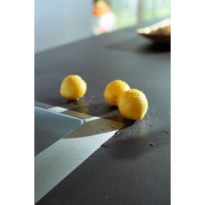 Hansgrohe S712-F660 vask i rustfrit stål med tre gule citroner og vanddråber på den mørke bordplade.