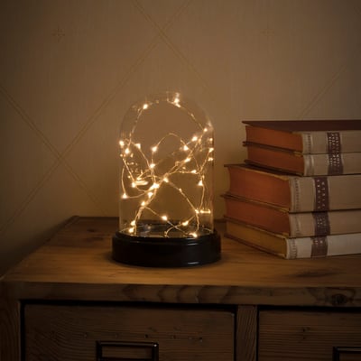 Nærbillede af Konstsmide glaskuppel med 30 amber LED-lys, der skaber en hyggelig stemning på en træoverflade.