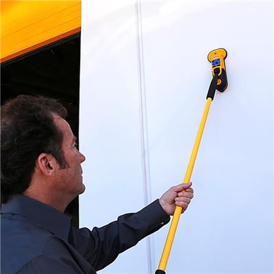 Mand bruger Zircon MT7 forlængerhåndtag til at scanne en hvid væg, en gul garageport ses i baggrunden.