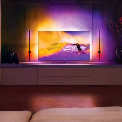 80cm RGBIC væglampe med Bluetooth, monteret på væggen bag et TV og afgiver farvet lys i rummet.