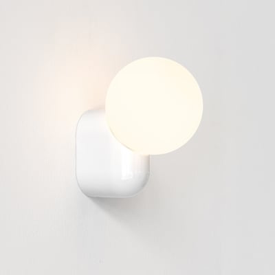 Astro Lyra Wall Single væglampe i hvidt porcelæn med rund, lysende skærm og blødt afrundet vægbeslag.