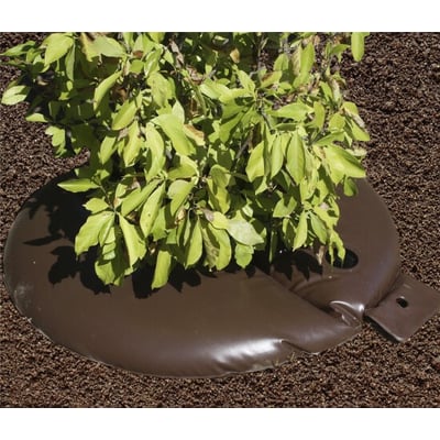 NSH Nordic Byggros vandingspose fyldt med vand omkring en busk, lavet af brunt UV-bestandigt PVC.