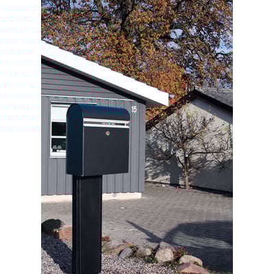 Assa Abloy Allux KS 200S postkasse i sort stål monteret på sokkel i forhave med efterårsfarver og hus i baggrunden.