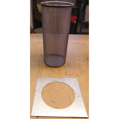 Streno universal brøndfilter og den medfølgende monteringsplade ligger på et træbord, klar til installation.