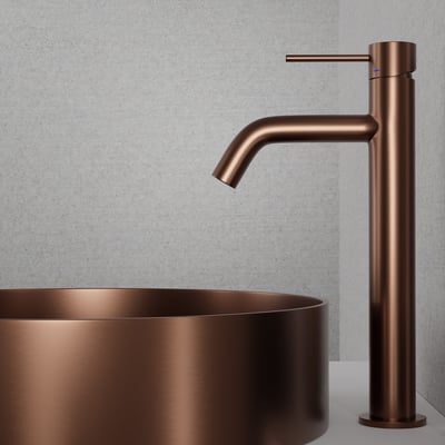 Scandtap Steel Voyage High Amber håndvaskbatteri i kobberfinish står ved en rund vask, set skråt fra siden.