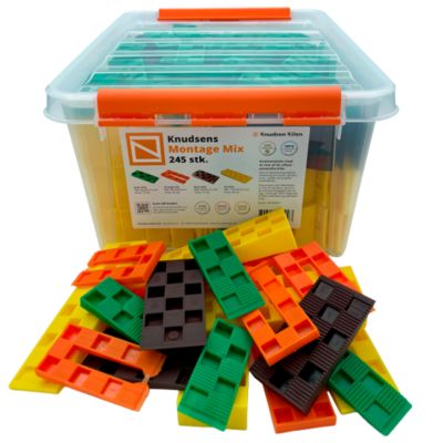 Knudsen Kilen montagemix med 245 plastkiler i grøn, orange, brun og gul, vist foran en gennemsigtig plastboks.