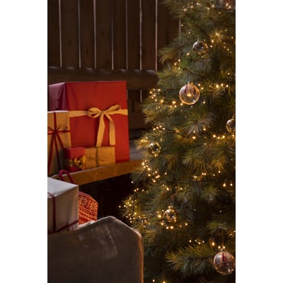 Konstsmide lyskæde med 200 amber frostede lys på et juletræ med gaver i baggrunden.