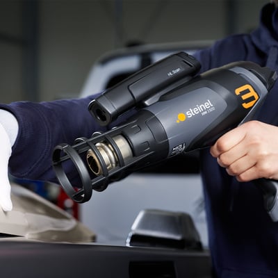 Steinel HM 1920 E varmeluftpistol holdes i hånden, viser forbedret tyngdepunkt og ergonomisk design til professionel brug.