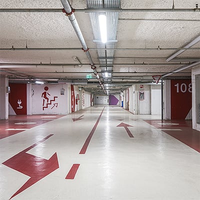 THORNeco JULIE polyesterarmaturer monteret i en lang parkeringskælder med betonloft og tydelige markeringer på gulvet.