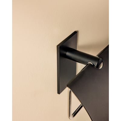 Cosmic toiletpapirholder med låg i mat sort, monteret på lys væg.