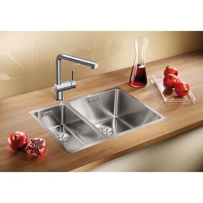 Blanco Andano 340/180-IF/N UXI køkkenvask i rustfrit stål med to kummer og en moderne armatur på en træbordplade.