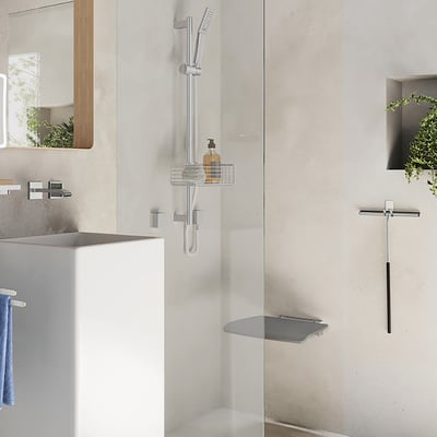 Smedbo living væghængt klapsæde monteret i et moderne badeværelsesmiljø med krom detaljer og gråt sæde.