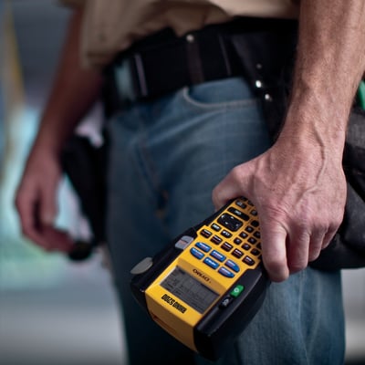 Mand holder DYMO® Rhino 5200 Pro labelprinteren i hånden, klar til industriel mærkning.