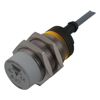 Carlo Gavazzi induktiv aftaster M30 med grå front, forniklet messinghus og kabel, set skråt forfra.