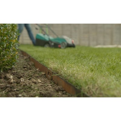 ECCO Products Core Edge kantskinne i corten stål, 1000 mm lang, ses i brug med en plæneklipper bagved på en grøn græsplæne.